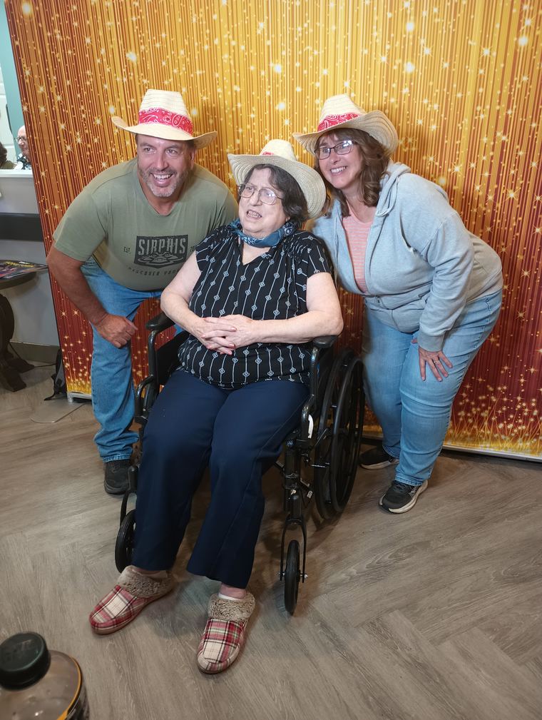 Guest using a wheelchair posing with two other adults in the photo booth area